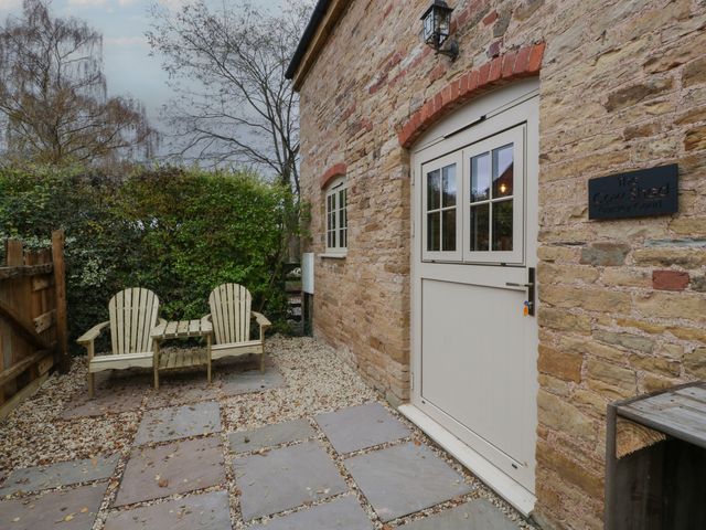 An outdoor area with chairs and a sign at The Cow Shed in Ross-on-Wye