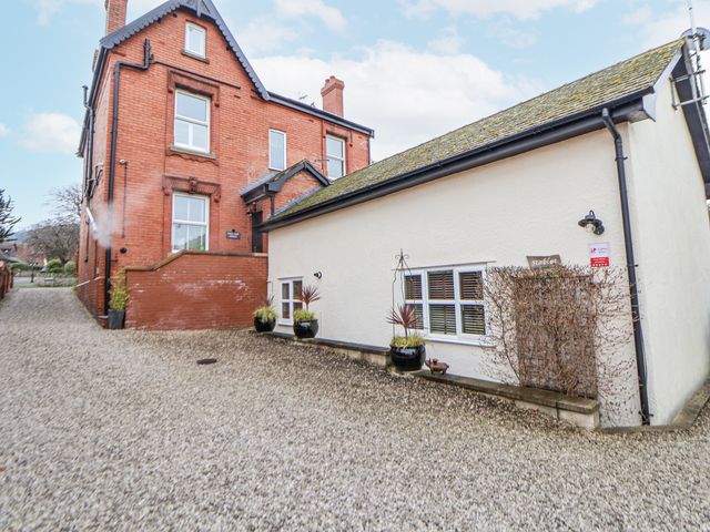 An outdoor view of The Stables in Prestatyn with a gravel driveway and nearby buildings