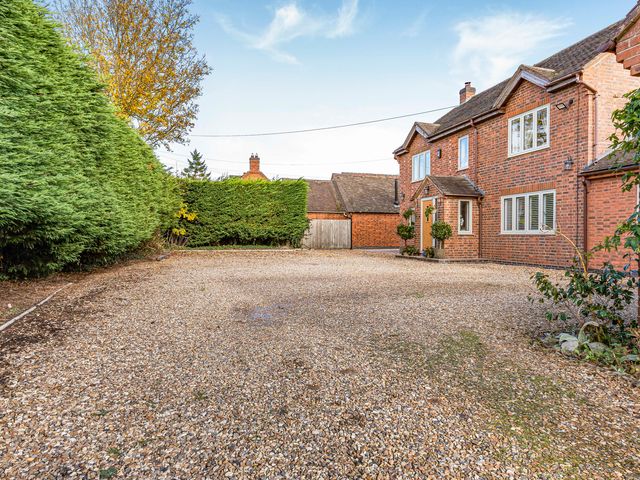 An outdoor area with a gravel driveway and hedges at 2 Mere Pits Cottages in Tamworth