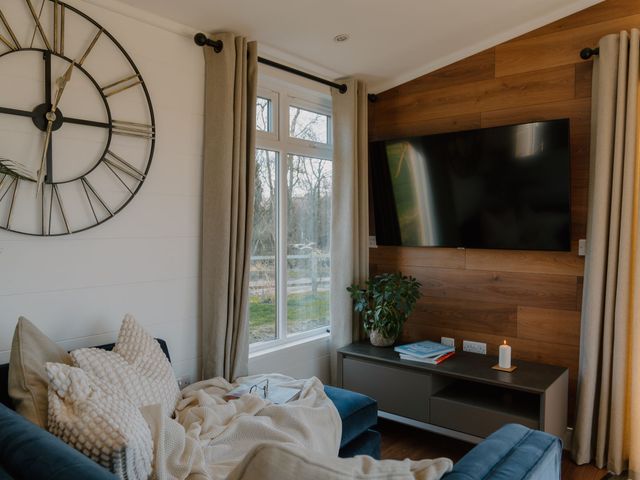 A living room with a clock and television at The Elton in Kings Cliffe