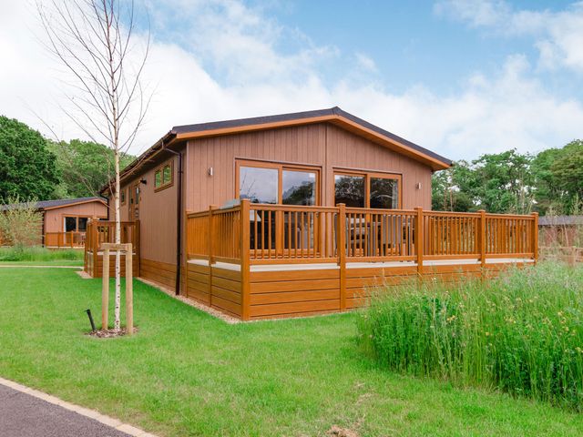 A wooden cabin with a deck and grass area at The Apethorpe (Pet) Kings Cliffe