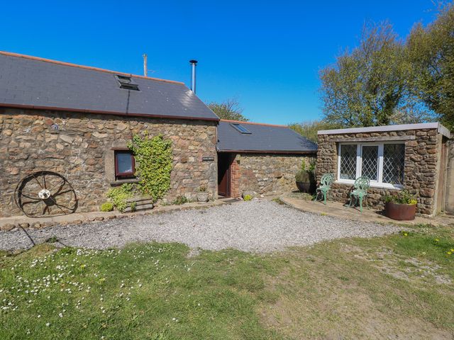A stone cottage with a gravel path and seating area at Ramsgrove in Pilton