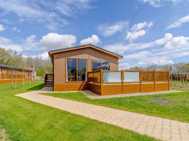 A wooden cabin with a deck and pathway at The Yarwell in Kings Cliffe