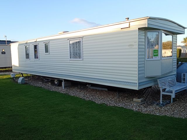 A mobile home on gravel with grass around at Atlas Moonstone