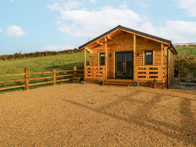 A log cabin with a gravel driveway and fence at Glenview Log Cabin in Ballycastle