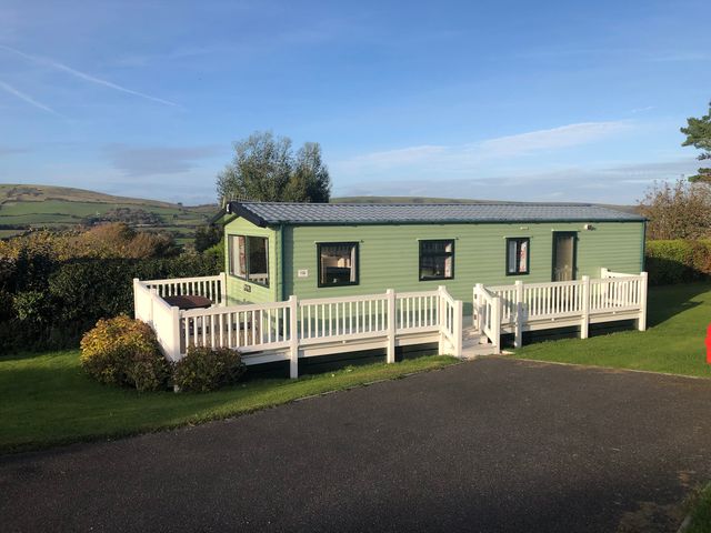 A caravan with decking and windows at Swanage Coastal Park Caravan in Swanage