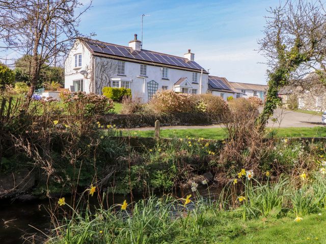 A house with a garden and stream at Ty Crigyll in Caergeiliog