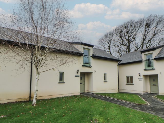 Two buildings with grass and a pathway at Ivy Cottage in Swansea