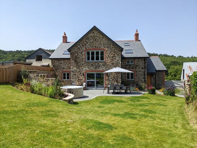 A house with patio furniture and a hot tub at Knowle House Okehampton