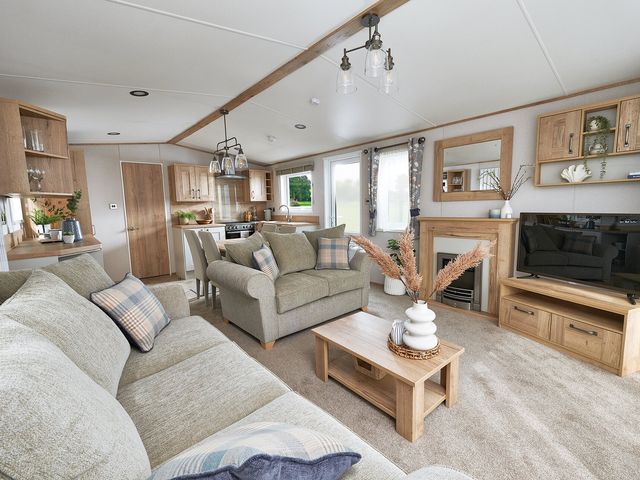 A living room with a sofa and television at Juniper Waterside Spa in Carlton Miniott near Thirsk