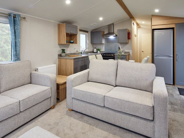 A living room with sofas and a kitchen area at Banyan Waterside Spa Carlton Miniott near Thirsk