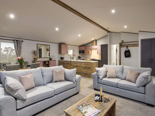 A living room with sofas and a kitchen in Laurel Spa Carlton Miniott near Thirsk