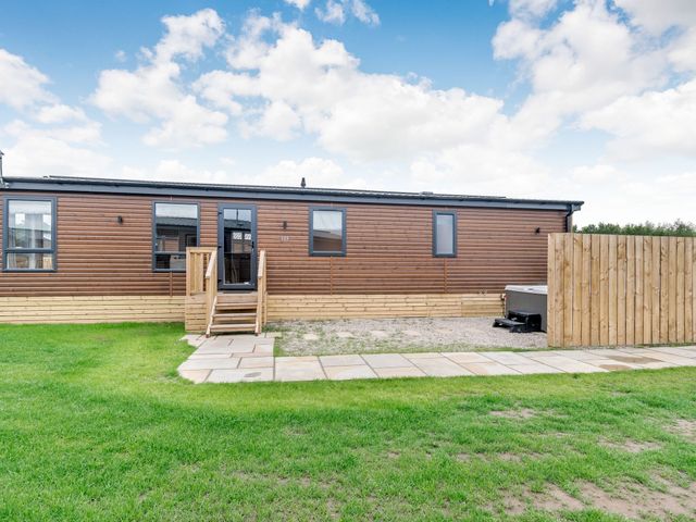 An outdoor view of a mobile home with steps and a fence at Beech Waterside Spa Carlton Miniott near Thirsk