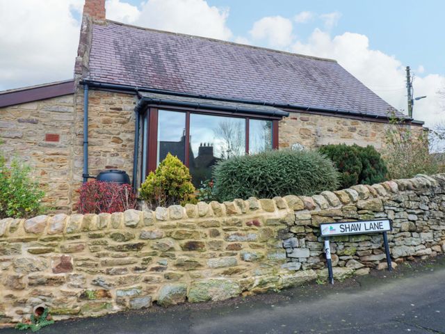A house with a stone wall and a street sign at Mains Cottage in Consett