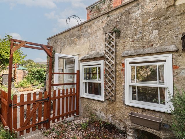 An outdoor area with a wooden gate and windows at Garden Studio at Stanley House in Charmouth