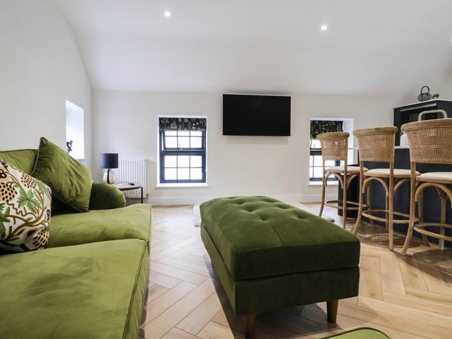 A living room with a green sofa and television at The Old Bakehouse in 
