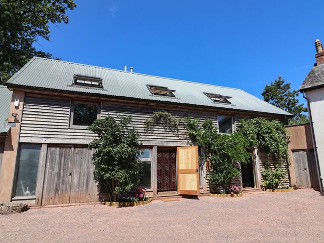 An exterior view of a building with wooden facade and plants at Captains Barn Tiverton