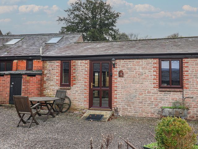 An outdoor view of a stone building with a table and chairs at Apple Cottage in Whitchurch Canonicorum