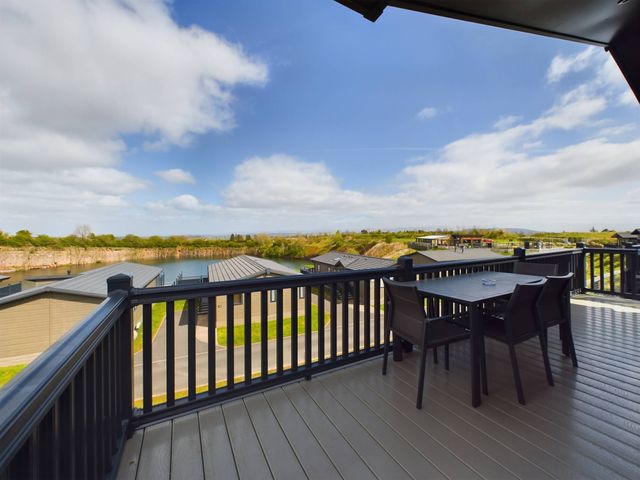 A balcony with a table and chairs overlooking a lake at Keswick in Penrith