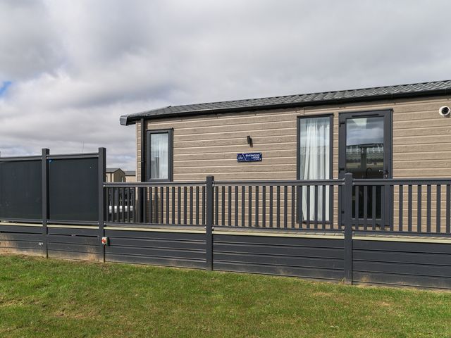 A mobile home with windows and a fenced area at Blencathra Spa (Pet) in Penrith