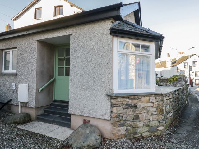 An exterior view of a house with a green door and stone wall at Renes Shop in Grange-Over-Sands
