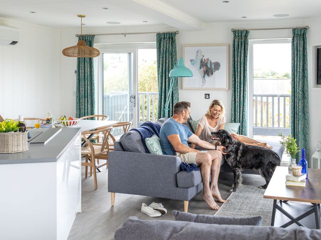 A living room with a couple and a dog at Signature Lodge Pet 8, Portreath