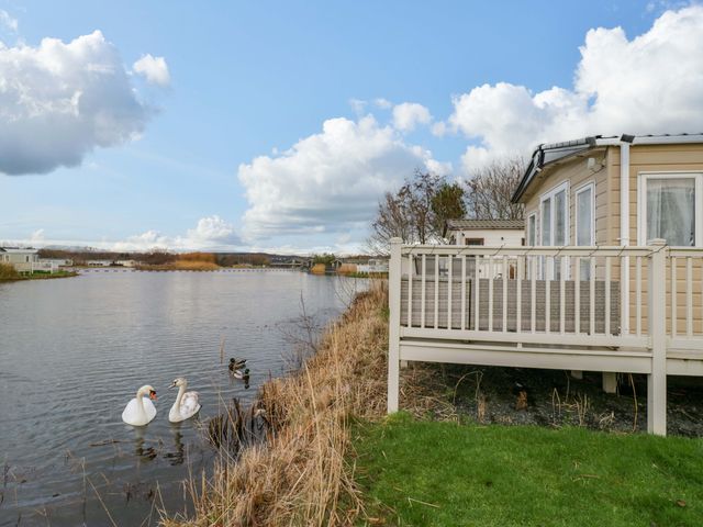 A deck by the water with swans and ducks at 62 Guddlebeck in Flookburgh