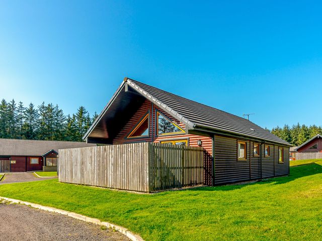 A house with a fence and trees at Rainbow Spa Plus Dundee