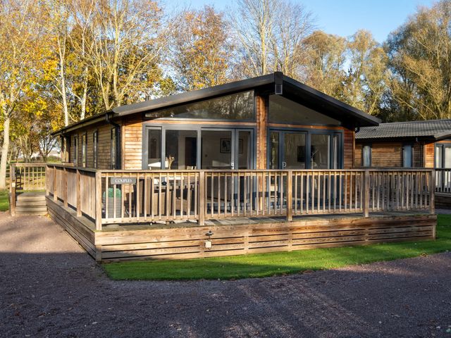 A wooden cabin with a deck surrounded by trees at Wentworth in Waltham