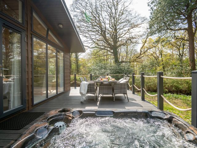 An outdoor area with a hot tub and dining table at Argel Spa Pet in Praze-An-Beeble
