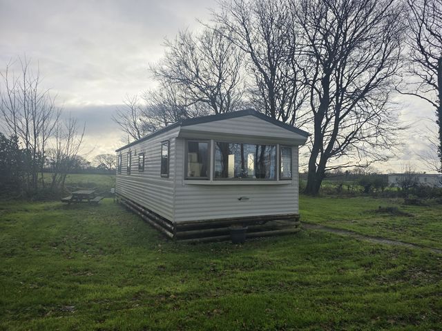 A caravan surrounded by trees and grass at Caravan 5 at Blackmoor Farm near Tenby