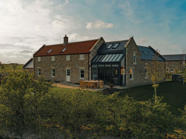An exterior view of a house with a garden and seating area at Mill Farm House Beadnell