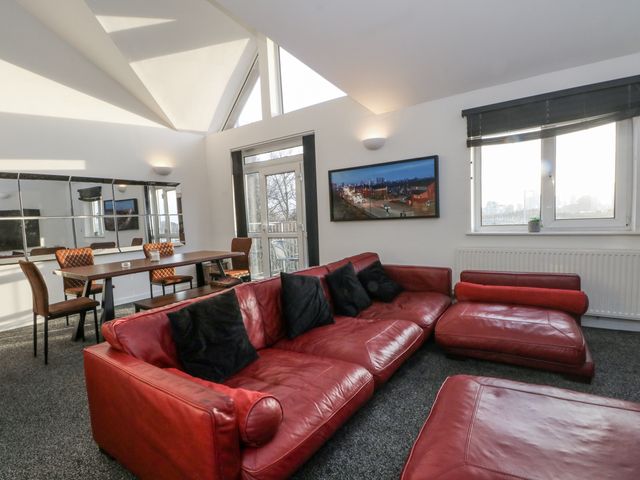 A living room with a red sofa and dining area at Manchester apartment in Manchester