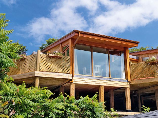 A modern building with a balcony and glass doors at Piran Spa Lodge Pet in Perranporth