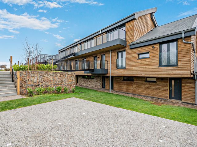 An outdoor view of a building with a balcony and garden at Arvor Suite 1.0 Marhamchurch