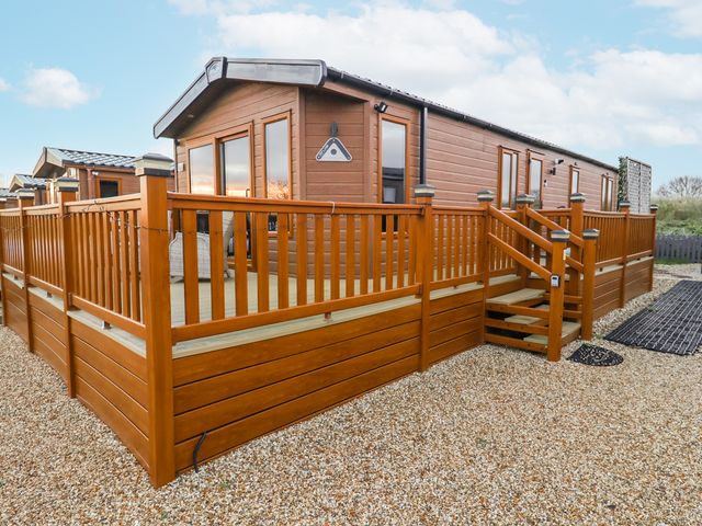 A cabin with decking and steps at Lakeside Lodge in Stonham Aspal