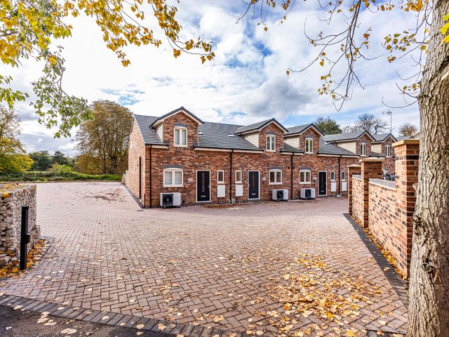 A exterior view of brick houses with a paved driveway at 6 Riverside Mews in Derby