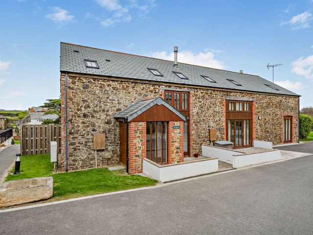 An exterior view of a stone house with multiple windows at Sand Parks in Marhamchurch