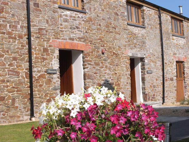 An outdoor view of stone buildings with doors and a flower pot at Westcotts in Marhamchurch