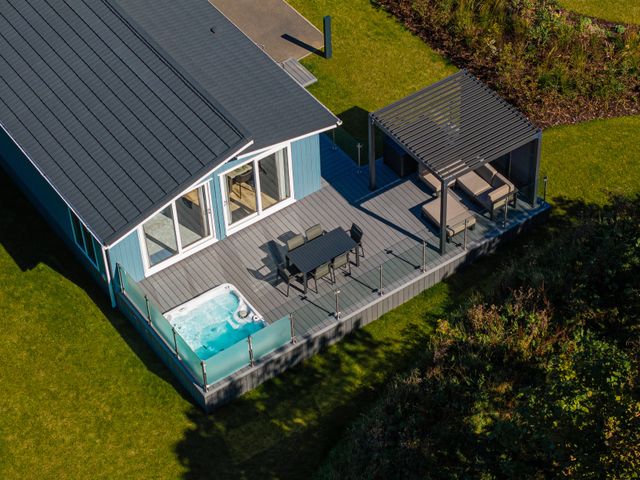 An outdoor area with a hot tub and dining table at Mullion 2 Spa, Bude