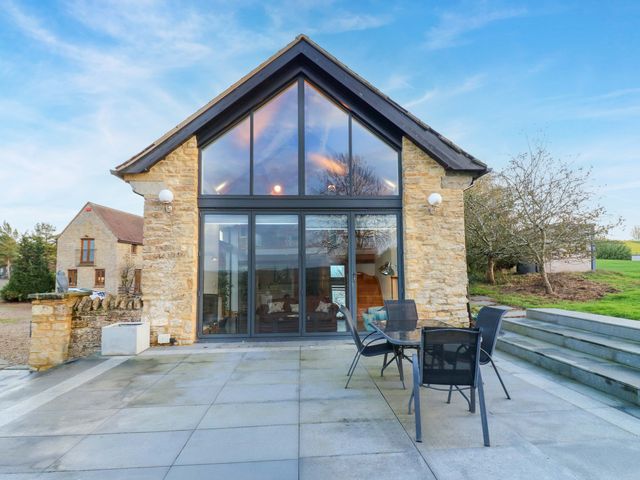 An outdoor area with a stone building and patio furniture at The Lodge @ Lodge Farm Bedford