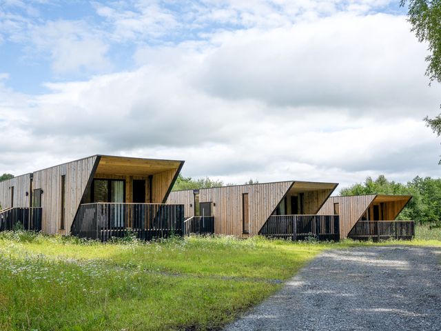 Three wooden cabins with balconies in a grassy area at Orka 2.0 Kinder (Pet) Dumfries