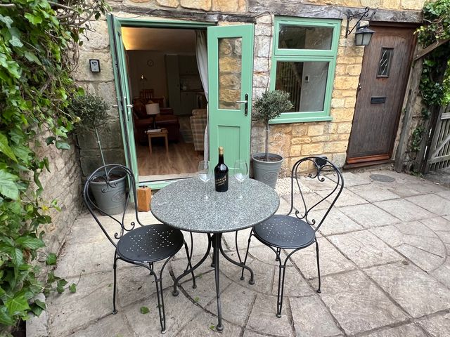 An outdoor patio with a table and chairs at Wheelwright Cottage in Moreton-In-Marsh