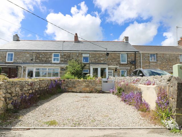 A house with gravel parking and flowers at Driftwood Cottage in Helston