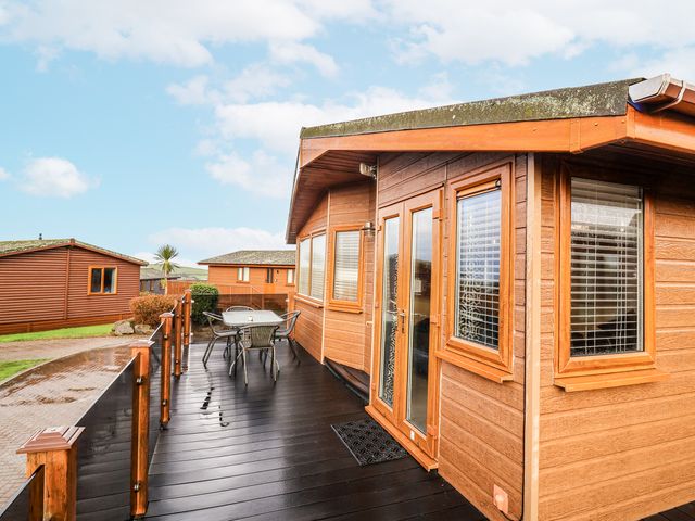 A wooden cabin with a deck and outdoor furniture at Ocean View in Ilfracombe