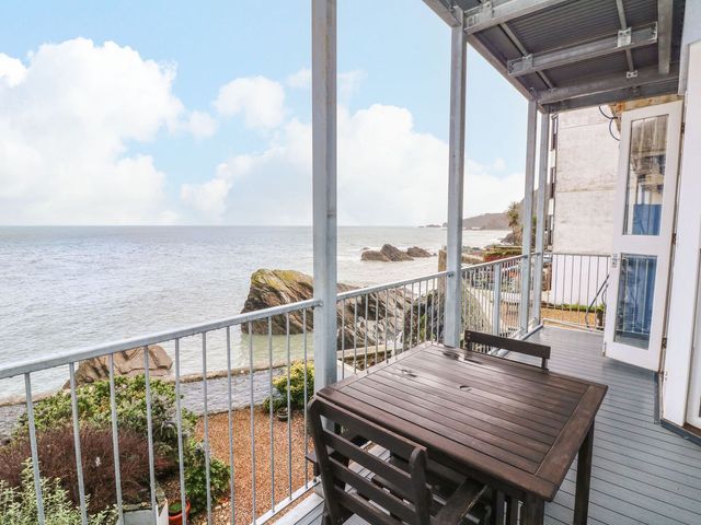 An outdoor balcony with a table and chairs overlooking the ocean at Val's Seaview in Ilfracombe