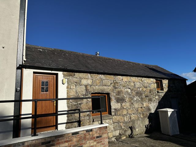 An outdoor view of a stone building with a wooden door and window at The Rocks in Newry