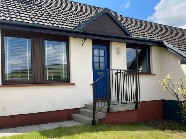 An exterior view of a house entrance with blue door and steps at 9 Creag An Iolaire near Portree