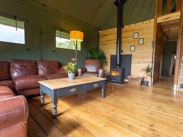 A living room with a sofa, coffee table, and wood stove at Badger - Luxury Glamping Retreat in Battle