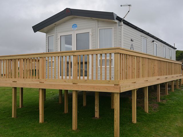 A cabin with a deck and windows at 601 Cribbar Cove in Perranporth